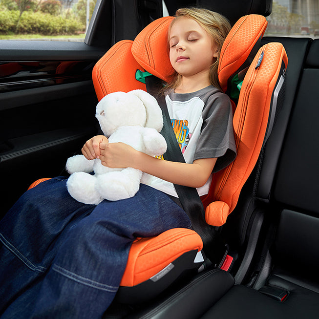 Barn sover i Recaro Axion 1 autostol i orange farve med en bamse i armene