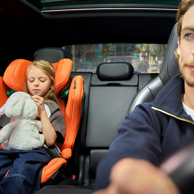 Barn i Recaro Axion 1 autostol i orange farve på bagsædet, mens far kører bilen