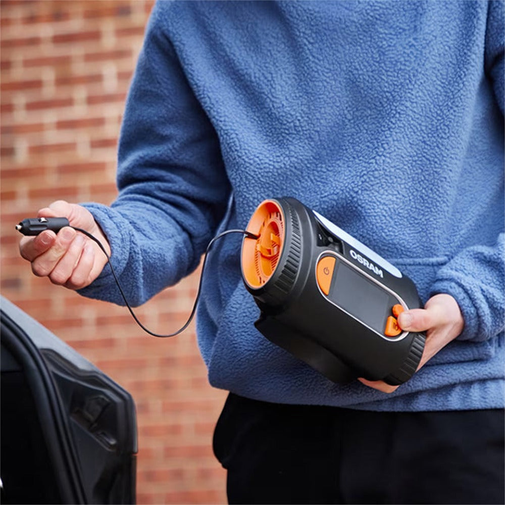 Person holder Osram TYREinflate 2130 kompressor med ledning, klar til brug ved bil