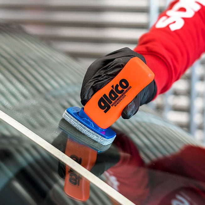 Hånd med Glaco DX glasforsegler på bilrude i nærheden af hvid tape