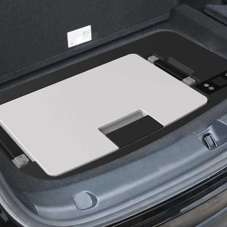 Køleskab monteret i bilens bagagerum med grå låg.