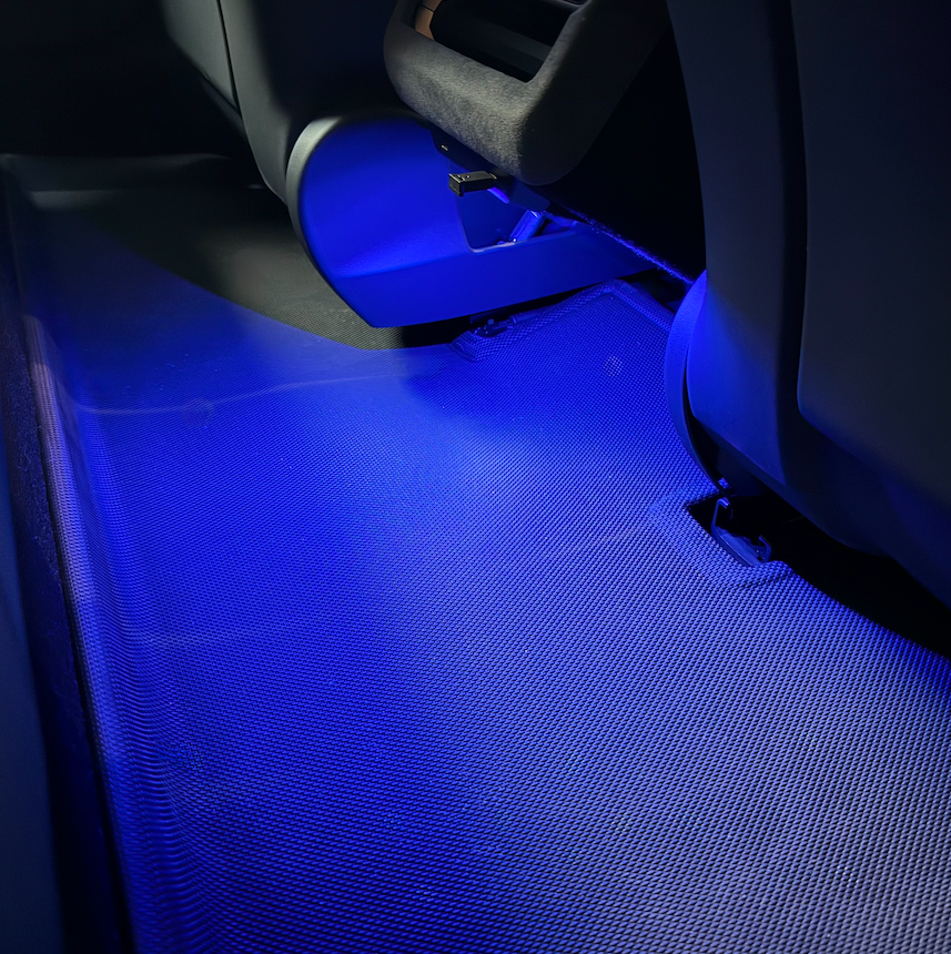 Blåt LED lys skinner ned på en måtter bagved sæderne.