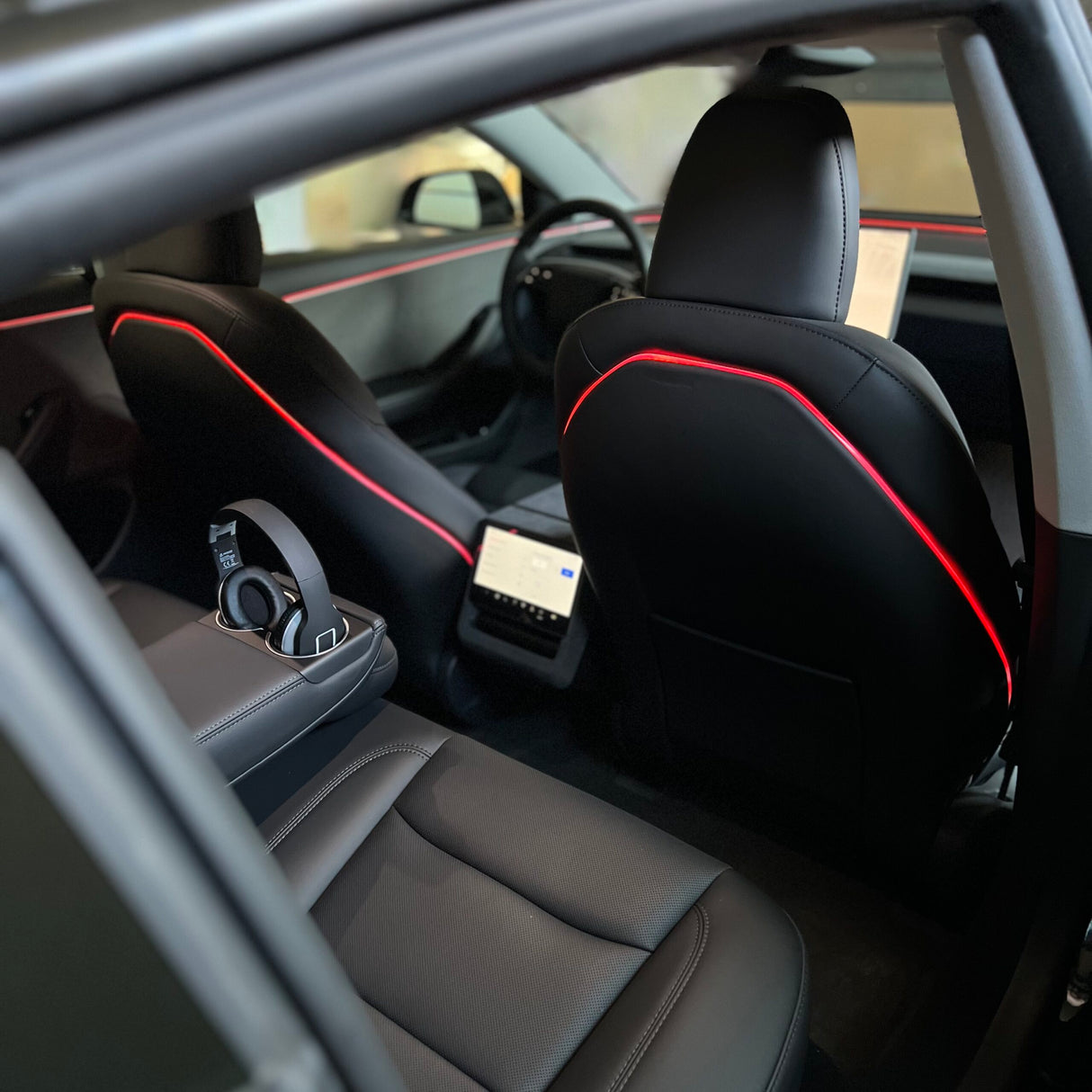 Rødt ambientelys langs plastikryglænet på forsæderne i en Tesla Model 3 Highland