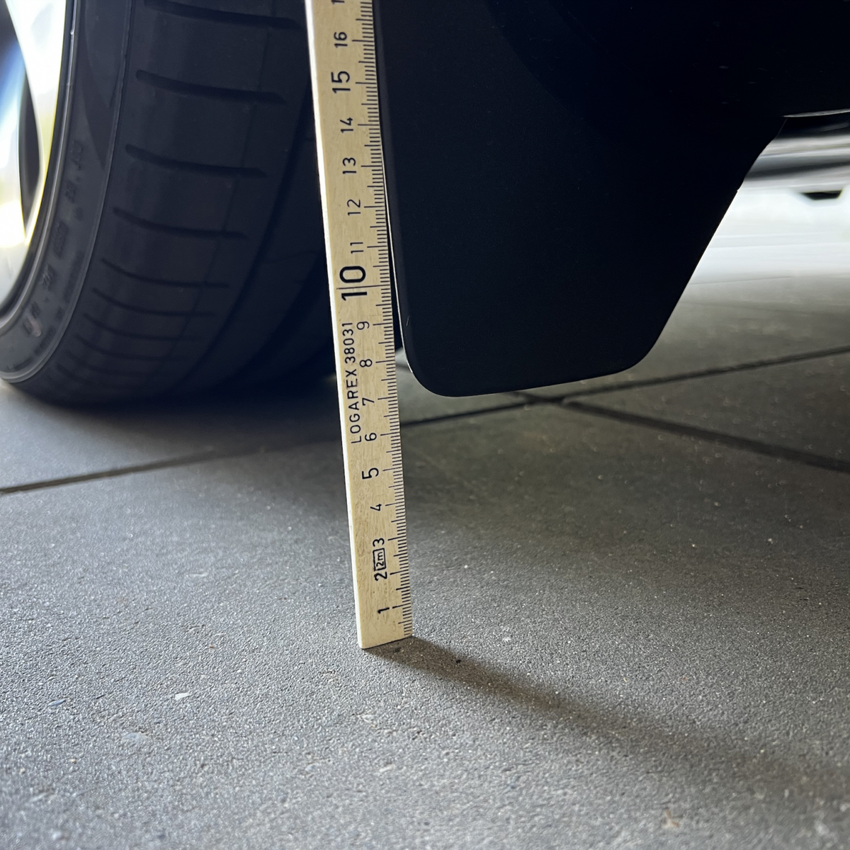 Originale stænklapper på Tesla Model Y målt med lineal.