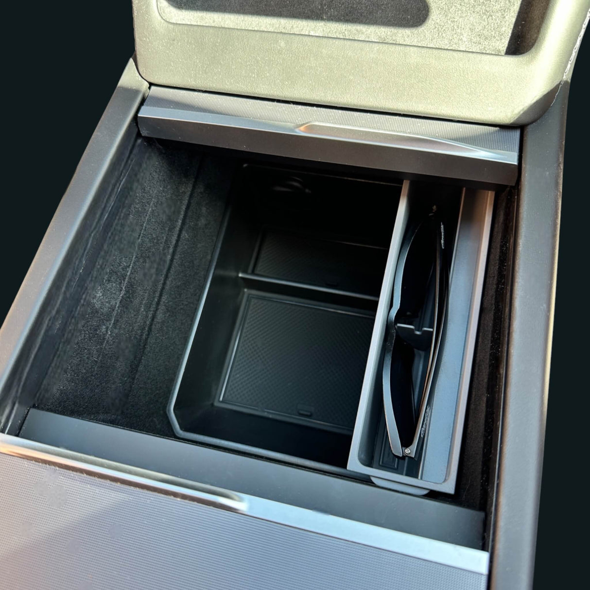 Solbrilleholder installeret i midterkonsollen på en Tesla med solbriller placeret i holderen.