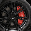 Røde bremsekaliber-covers med hvidt Tesla logo på en sort fælg.