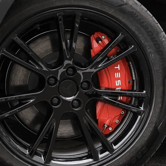 Røde bremsekaliber-covers med hvidt Tesla logo på en sort fælg.