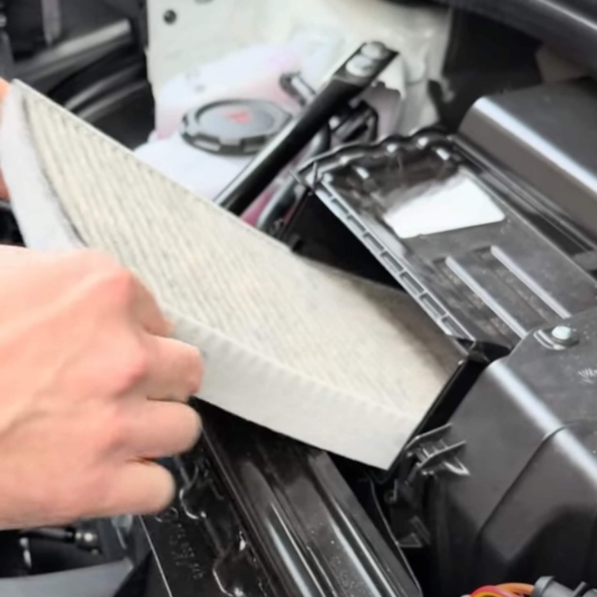 En hånd indsætter et kul luftfilter i motorrummet på en VW ID.3/4/5/6/7.