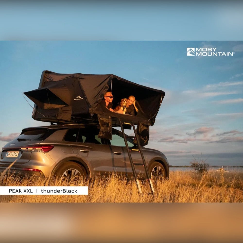 Par i Moby Mountain Peak XXL tagtelt i thunderBlack på Audi e-tron ved solnedgang