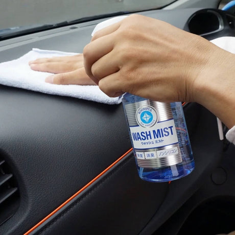 Soft99 Wash Mist interiørrens sprayes på bilens instrumentbræt, som derefter tørres af.