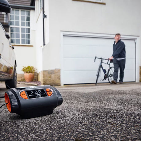 Osram TYREinflate 2130 kompressor på indkørsel med mand og cykel i baggrunden