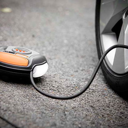 Osram TYREinflate 450 mini-kompressor på asfalt tilsluttet et bildæk