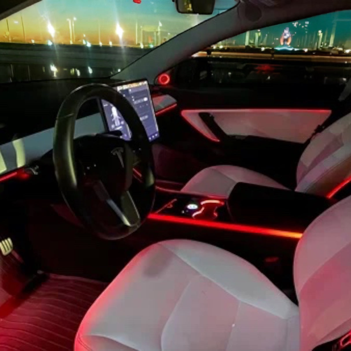 Ambient interiørlys oplyser kabinen i en Tesla Model 3/Y med rød belysning på døre og konsol.