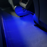 Blåt LED lys skinner ned på en måtter bagved sæderne. 