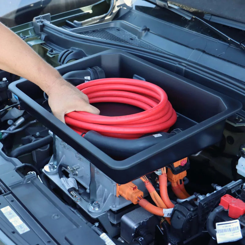 Mand placerer rødt ladekabel i Rati frunk beholder monteret i en bil