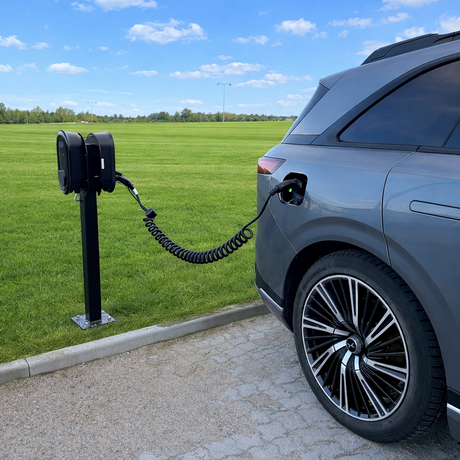 Et sort spiral ladekabel som er tilsluttet en ladeboks og i en elbil