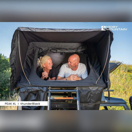 To personer ligger i Moby Mountain Peak XL tagtelt i thunderBlack på Land Rover Defender