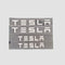 Fire sæt TESLA bogstav-emblemer i forskellige størrelser på lys baggrund