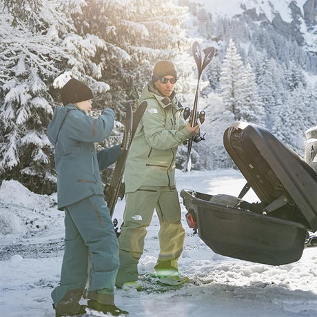 Skiløbere tager ski ud af Thule Arcos XL bagageboks 450L i skoven om vinteren